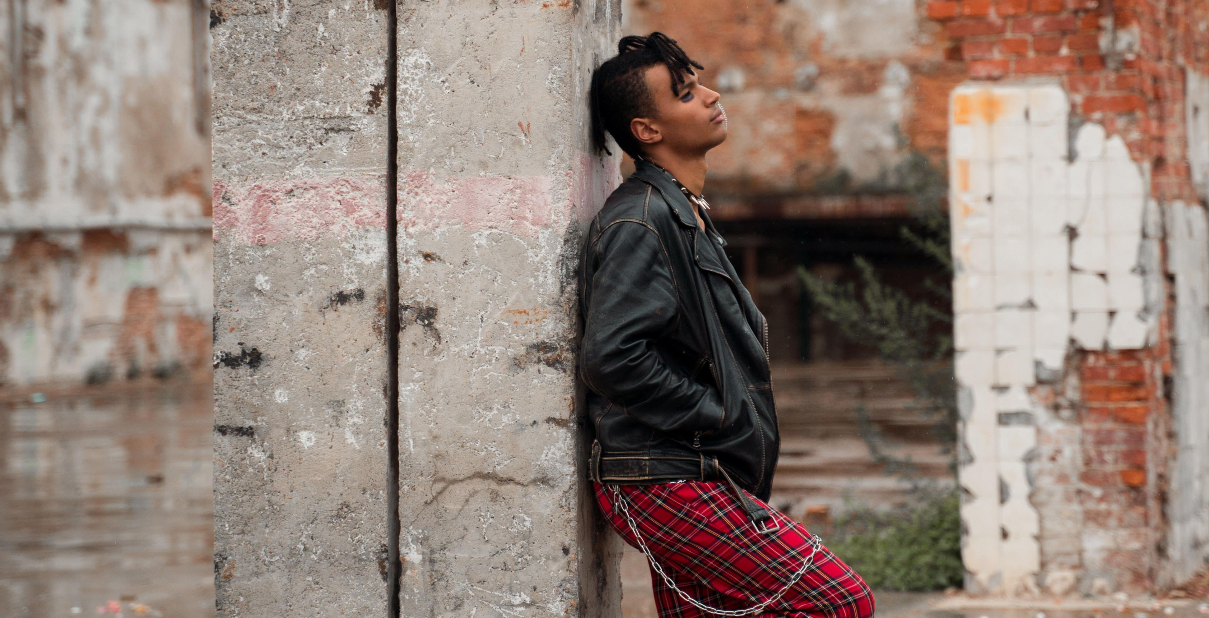 A young person of color with red and black anarchist clothing.